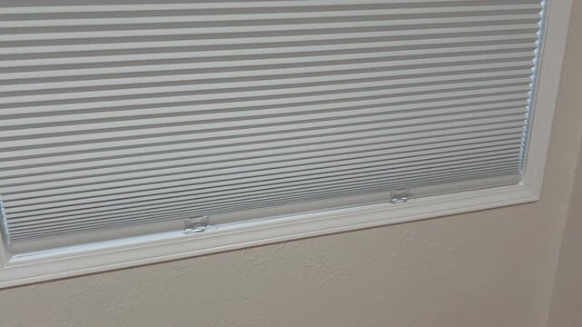 Hand Pulls White Window Blind Cord in Bright Room