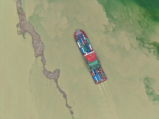 A cargo ship sails through Yichang Three Gorges, China, navigating the water near a sandbar.