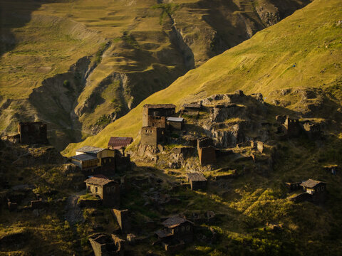 Aerial view of ancient stone dwellings cling to the rugged cliffs of Dartlo, bathed in the warm glow of the setting sun, Dartlo, Kakheti, Georgia.