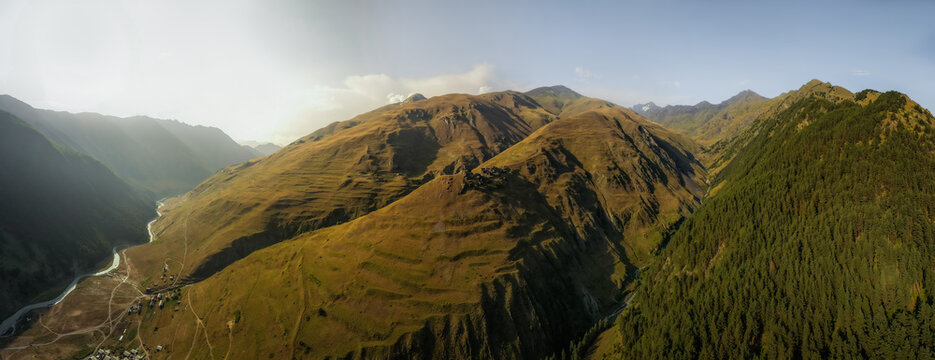 Aerial view of golden sunlight kissing the rugged peaks and verdant valleys near Dartlo, Kakheti, Georgia.