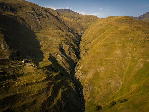 Aerial view of sun-kissed slopes and dramatic gorges carve through the rugged terrain, a stark yet beautiful scene from above, Dartlo, Kakheti, Georgia.