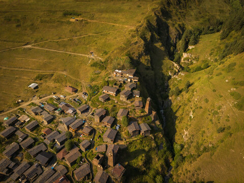 Aerial view of the village of Dartlo nestles amongst golden grasslands and the steep gorge carved by a rushing stream, Dartlo, Kakheti, Georgia.
