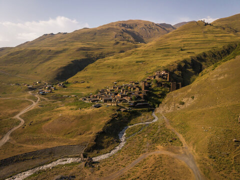 Aerial view of ancient stone towers and dwellings nestled among rolling hills, with a winding river cutting through the landscape, Dartlo, Kakheti, Georgia.