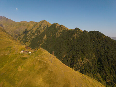 Aerial view of ancient stone towers nestled amidst the rolling green hills and rugged peaks of the Caucasus mountains, Dartlo, Kakheti, Georgia.