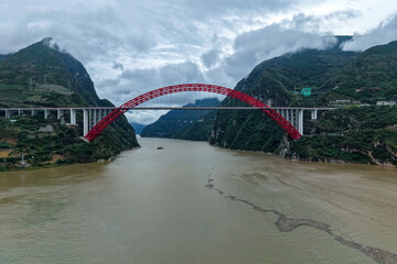 Yichang Three Gorges China bridge spans a wide river with green mountains under clouds.