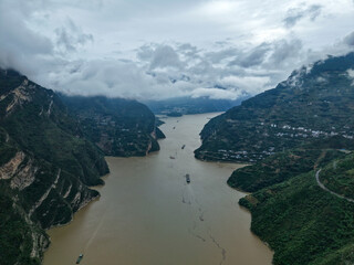 Yichang Three Gorges China mountains rise above a wide river with boats sailing through the misty...