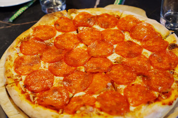 Delicious pepperoni pizza served on wooden board at a restaurant table