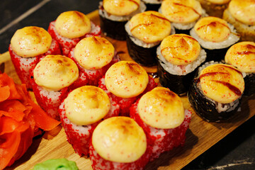 Colorful sushi platter with baked toppings served on a wooden board