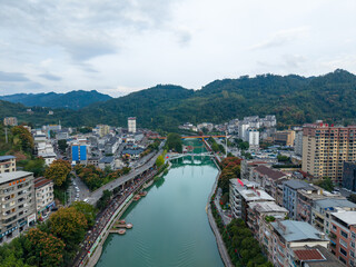 Xuan'en County shows a flowing river and buildings nestled among green hills in China.