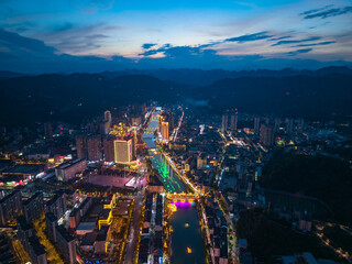 Xuan'en County Hubei Province China city lights gleam across the landscape at dusk illuminating the river and buildings below.