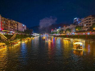 The river flows through Xuan'en County at night with boats illuminated by lights.