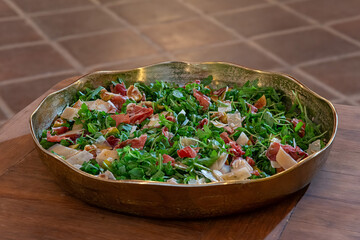 Fresh arugula salad topped with slices of prosciutto and cheese, a healthy and flavorful Mediterranean-style dish.