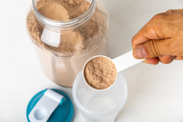 Protein shake with protein powder on a colored background. The powder is mixed with water or milk. A dietary supplement for a balanced diet. Whey protein. Fitness and gym diet nutrition.