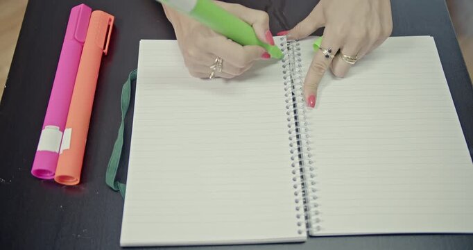 Captivating close-up of a person's hands using a green highlighter in a notebook. This visual and auditory experience symbolizes focus, creativity, and productivity for study or work.