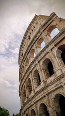 Vertical close-up photo of the famous Colosseum in Rome, Italy, captured in warm sunlight. Detailed view of the ancient Roman amphitheater showing arches, stone texture, and historical architecture