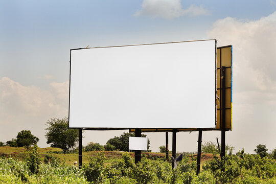 Billboard on rural area of India, outdoor advertising, mockup billing board in front of green tree and Blank white background for branding design large hoarding. Outdoor advertising construction.india