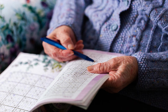 Senior person doing sudoku puzzle in book