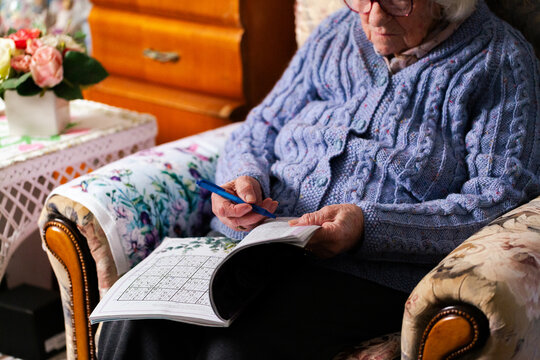 Senior person doing sudoku puzzle in loungeroom at home