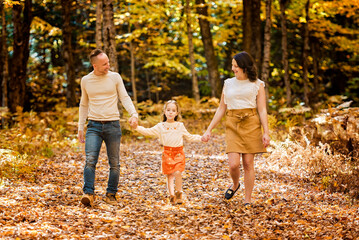 Fototapeta premium Mature family with daughter on a walk in autumn forest.