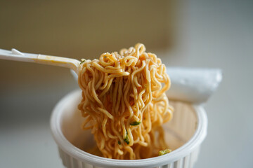 Close up of instant noodles in a cup with a plastic fork. A quick and easy meal, showcasing the convenience of modern fast food, ready to eat.