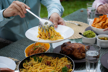 A delicious homemade feast on a dining table, featuring spaghetti carbonara, roasted chicken, and various side dishes. A concept for family gatherings and celebrations.