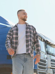 Fototapeta premium Truck driver smiling looking away next to vehicle