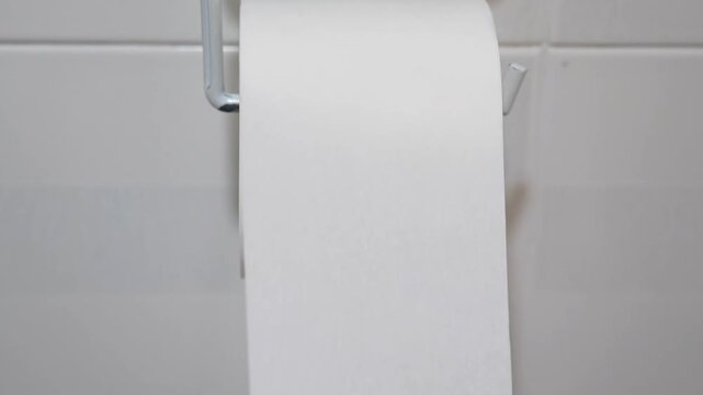 Close-up a hand unrolls a roll of toilet paper in a bathroom. Health problems