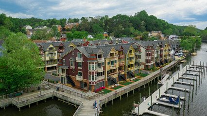 Aerial view of colorful townhouses with intricate architectural details line a waterfront boardwalk, juxtaposed against the lush green trees, Woodbridge, Virginia, United States.