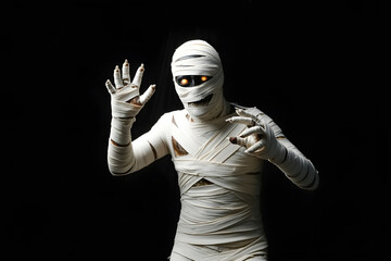 Studio shot portrait of young man in costume dressed as a halloween cosplay of scary mummy pose like a clamber acting on isolated black background
