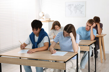 Fototapeta premium Students taking exam at wooden table indoors
