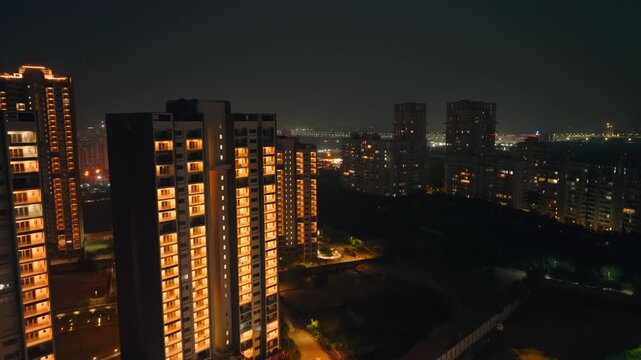 Aerial view of Orris Aster Court apartments aglow against the dark night, contrasting with the distant city lights, Gurugram, Haryana, India.