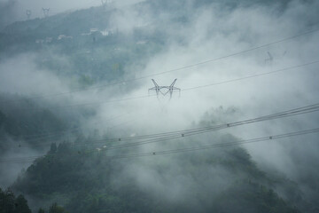 Power lines stretch across a misty, mountainous landscape in Yichang, China, as fog envelops the...