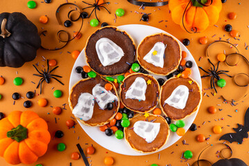 Tasty Halloween pancakes topped with marshmallow ghosts. Halloween morning dessert, for breakfast or brunch, with colorful candies, sweets and Halloween decorations