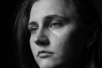 Sad woman crying on dark background, closeup. Black and white effect