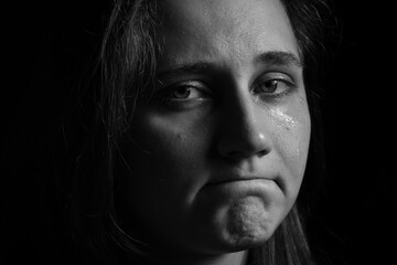 Fototapeta premium Sad woman crying on dark background, closeup. Black and white effect