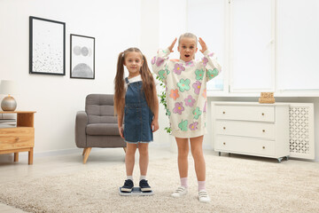 Little girl standing on scales and her friend at home