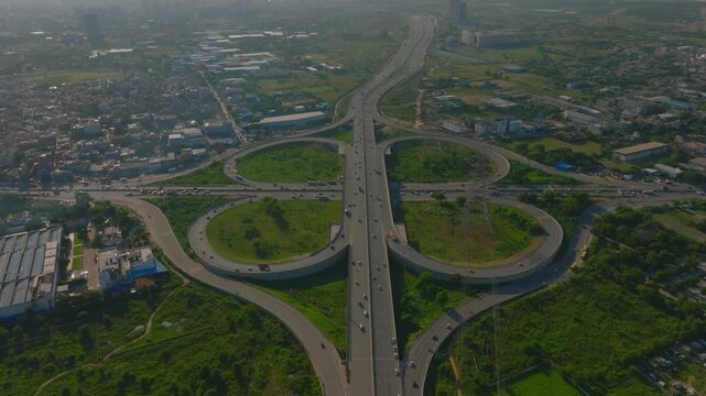 Aerial view of a complex cloverleaf interchange showing the intricate highway system amidst lush green spaces, Gurugram, Haryana, India.
