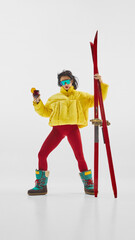 Stylish woman in yellow jacket with red skis and drink posing confidently. Concept of winter...