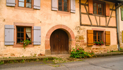 Fototapeta premium Charming old stone house with wooden shutters and arched doorway on a cobblestone street.