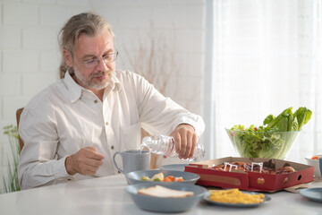 Senior elderly older grandfather stay at home with painful face sitting alone on eating table in house. Depressed elderly retired man upset feeling unhappy. Lonely and missing his family at home	
