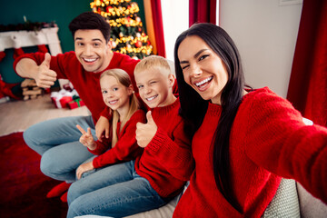 Happy family in festive sweaters enjoying Christmas eve with tree and decorations in cozy home atmosphere