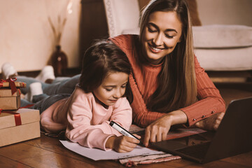 Asking For A Gift. Cute small girl writing wishlist letter mail to dear Santa Claus, cheerful woman...