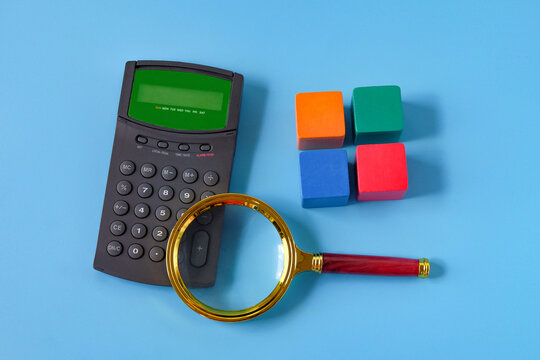 Magnifier glass with calculator and color wood cube.