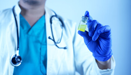 Close-up of a doctor or scientist's hand holding a vaccine vial. A vial of viral vaccine for injection is in the hand of a doctor or scientist technician. Concept of medicine and drugs.