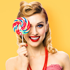 Half face portrait of happy expressive smile woman holds lollipop in front of one eye. Cute pin up girl in retro style image. Isolated yellow background. Ophthalmology concept. Square