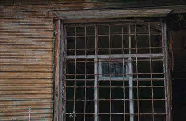 Rusted window bars frame a decayed wooden wall