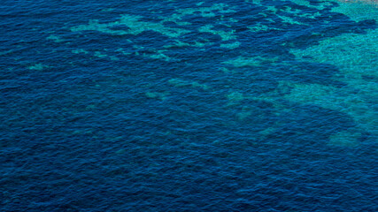 Aerial view of the azure sea surface. The water is calm and crystalline. Ideal for textures, patterns, and backgrounds.