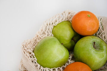 Organic Fruit Flat Lay - Eco Mesh Bag with Green Apples and Fresh Tangerines on White Background 