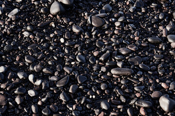 Close-up of wet black volcanic pebbles on the beach - natural texture background