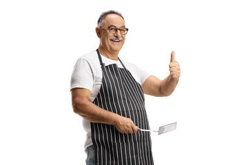 Mature man holding a turner utensil and gesturing thumbs up